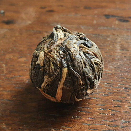Perles de thé puerh 'cru' de 8g sur table en bois